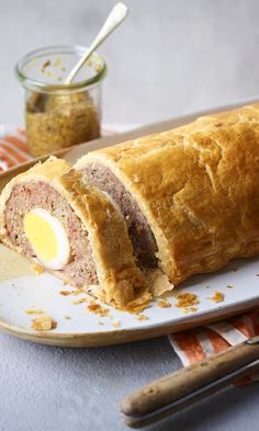 a meatloaf roll cut in half on a plate with a fork and knife next to it