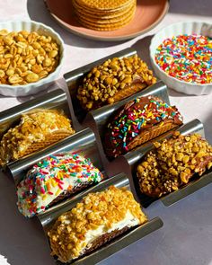 there are many different desserts in the trays on the table with each one