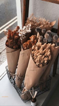 three cones filled with dried plants sitting on top of a wooden chair next to a window