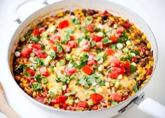 a casserole dish with tomatoes, corn and cilantro on the side