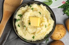 mashed potatoes with butter and parsley in a bowl next to two wooden spoons