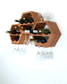 a wooden wine rack with several bottles and glasses on the top, hanging from a wall