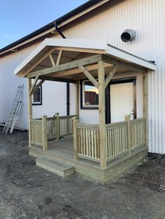 a wooden gazebo sitting next to a white building