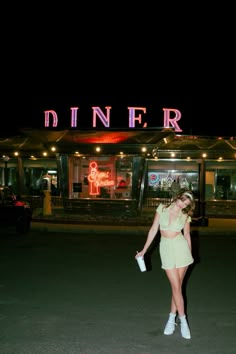 a woman standing in front of a diner at night