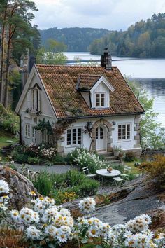 a house sitting on top of a lush green hillside next to a body of water