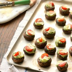 a tray filled with stuffed mushrooms covered in veggies next to a spatula