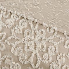 an embroidered fabric with white flowers and leaves on the bottom, along with a beige background