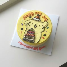 a yellow birthday cake with an elephant on it's face and the words happy new year written in red