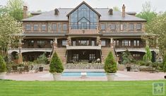 a large house with a pool in front of it and lots of greenery on the lawn