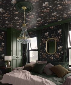 a bedroom with floral wallpaper, green walls and a chandelier hanging from the ceiling