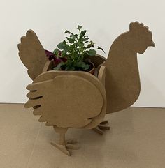 a planter shaped like a chicken holding a potted plant