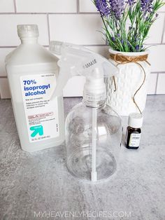 a bottle of alcohol, an empty glass container and some lavender flowers on a counter