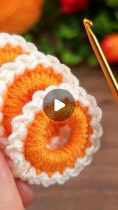 crocheted orange and white object being held by someone's hand