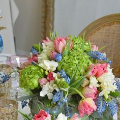 a bouquet of flowers sitting on top of a table next to glasses and vases