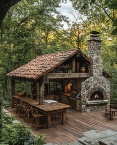 a wooden deck with an outdoor kitchen and fireplace in the middle surrounded by greenery