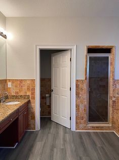 a bathroom with wood flooring and tile on the walls is pictured in this image