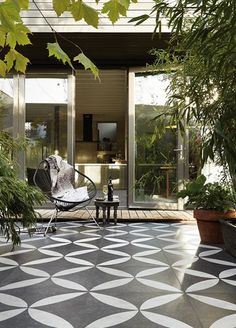 a black and white tiled patio with potted plants on the side, and a pink sign that says butten teegels nu te kop