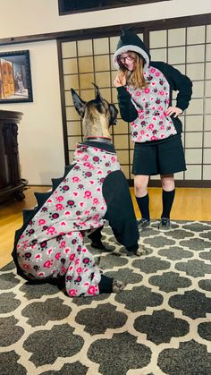 a woman standing next to a dog on top of a rug