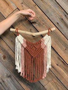 a woman is holding up a piece of yarn with two wooden sticks attached to it