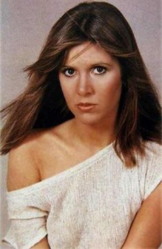 an old photo of a woman with long hair and wearing a white shirt, posing for the camera