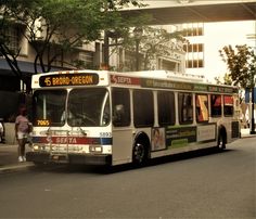 the city bus is parked on the side of the street as people walk by it