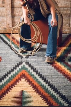 a man sitting on top of a chair with a rope in his hand and a cowboy hat