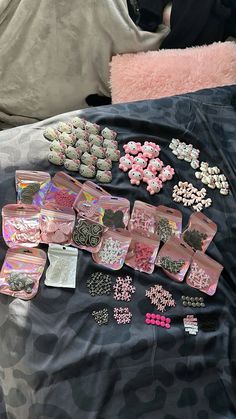 there are many pink and silver items on the bed, including earring pins and earrings