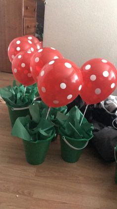 red and white polka dot balloons in green cups on the floor next to a black backpack