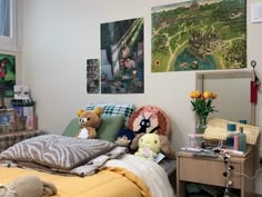 a bed with stuffed animals on it in a bedroom next to pictures and other items