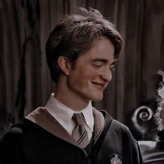 a young man wearing a harry potter robe and smiling at the camera with his eyes closed