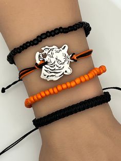 Tigers Sports Friendship Bracelet. Pura Vida style string, braided, woven, beaded, adjustable bracelet.  Fits most wrists and are stackable.  Perfect for everyday casual wear, activities, and special events. Can be worn individually or as a set.   Please reach out if you're interested in specific colors.  SIZING: Black Braided Bracelet:  6 - 11 inches Beaded Black and Orange Bracelet:  2.36 inches CARE: Bracelets are durable, but excess pulling or yanking may cause them to break. SPECIAL NOTES: Your new bracelet may be slightly sticky/tacky for a few days.  This will not last, but may make adjusting slightly difficult for a bit. Bracelets Braided, Wax Cord Bracelet, Orange Bracelet, Knot Bracelet, Bead Set, Cord Bracelet, Macrame Jewelry, Cord Bracelets, School Colors