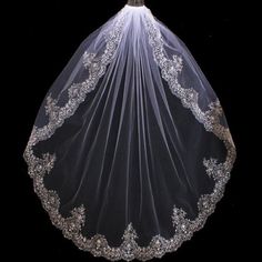 a wedding veil with lace on the bottom and beading around the edge, is shown against a black background