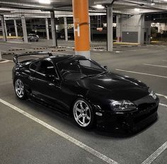 a black sports car parked in a parking lot next to an orange pole with lights on