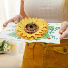 a woman holding a card with a sunflower on it