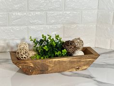 a wooden tray with plants in it on a marble countertop next to a white tiled wall