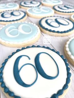 decorated cookies with blue and white frosting are on a glass tablecloth next to the number sixty