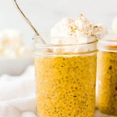 two jars filled with food sitting on top of a white cloth next to a spoon