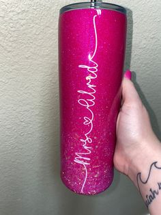 a hand holding a pink tumbler with writing on it