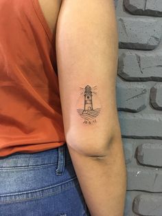 a woman with a small lighthouse tattoo on her arm