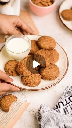 a person holding a plate with cookies on it and milk in the bowl next to them