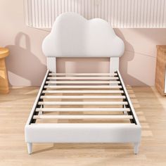 a white bed with a cloud shaped headboard and foot board in a pink room