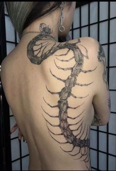 the back of a woman's shoulder with a scorpion tattoo on it