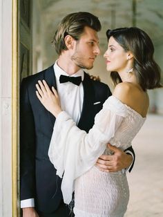 a man in a tuxedo and a woman in a white dress standing together