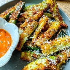 fried zucchini sticks with tomato sauce and parmesan cheese on the side