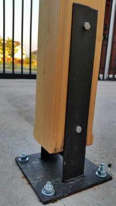 a close up of a wooden post with two bolts on the ground near a fence