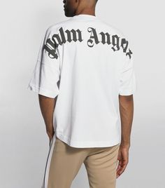 "Shorts sleeves t-shirt in white cotton with \"palm angels\" logo printed in black at collar and at back. crewneck collar. oversize fit. print executed on finished garment. this particular procedure makes each garment looks different, the print is irregular, especially near thicker areas where there may be fragmentation or colour build up. these distinguishing features are an effect that make this garment unique and are not to be considered flaws. these aspects may change with garment use and handling. fabric 100% cotton - rib detail 100% cotton" Palm Angels Top, Angel Shirt, Angels Logo, Oversized Silhouette, Classic Logo, Palm Angels, Harrods, Tshirt Logo, Oversized Fits