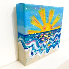 an acrylic painting of a sun over the ocean on a white wall with blue and yellow waves