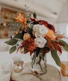 a vase filled with lots of flowers on top of a wooden table next to candles