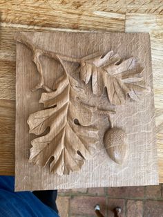 a wooden carving with leaves and acorns on it