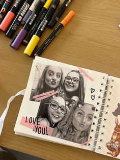 an open notebook with photos on it next to markers and crayons